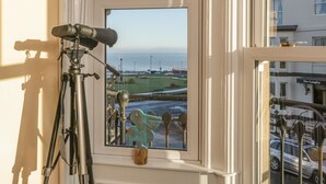 A telescope set up on a windowsill overlooking a coastal view, with a building labeled "The Langley" in the background. - Apartment 4 (Whitby)