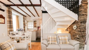A cozy living room with a sofa and a dining area with a table and chairs. - Dalesway Cottage (Windermere)