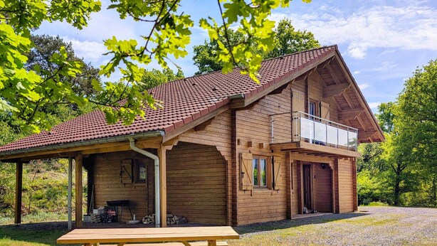 Une cabane en bois dotée d’une terrasse couverte et d’une table de pique-nique.