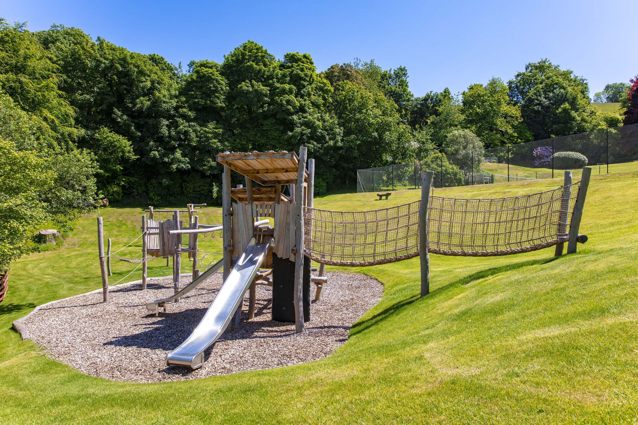 Un parque infantil con un tobogán, estructuras para escalar y una zona con red.
