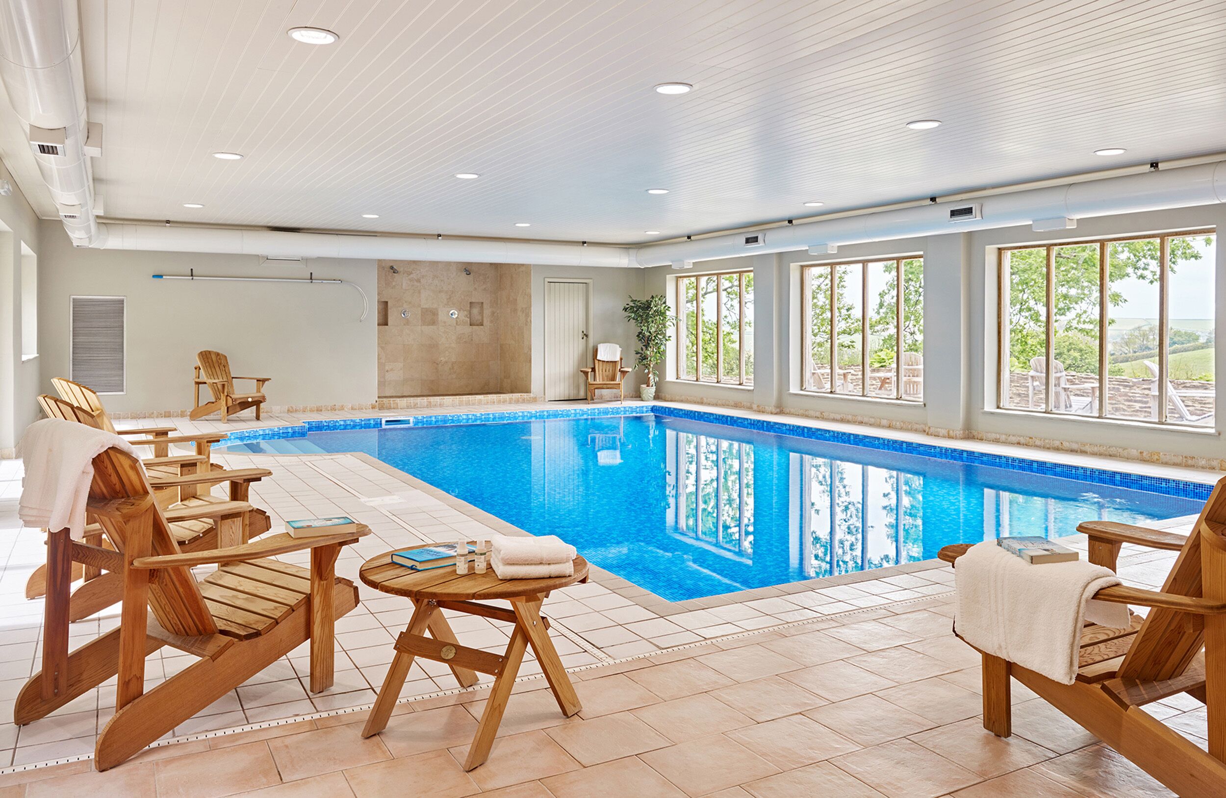 A swimming pool with wooden loungers and a view of the outdoors.