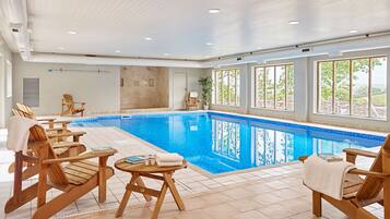 A swimming pool with wooden loungers and a view of the outdoors.