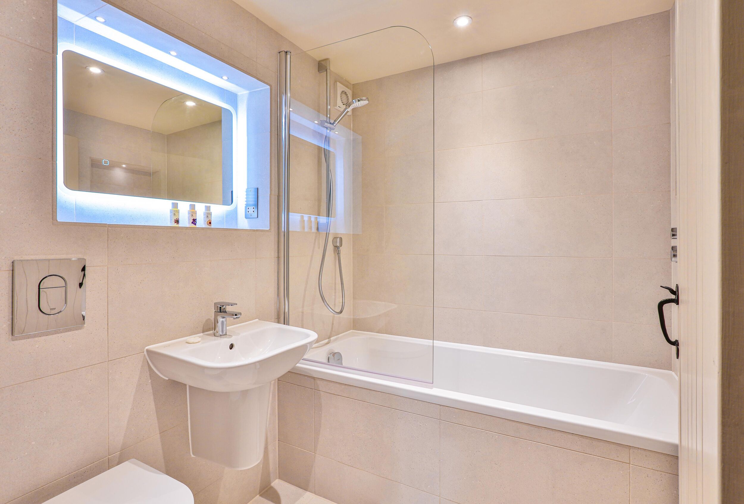 Une salle de bain moderne avec un grand miroir, un lavabo et une baignoire.
