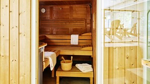 A wooden sauna room with benches, a table, and a bucket. - Garden House (Totnes)
