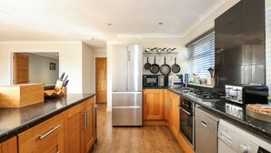 A modern kitchen with wooden cabinets, stainless steel appliances, and a built-in dishwasher. - Honeybees Haven (Hunstanton)