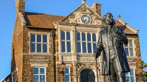 A historic building with a clock tower, a statue, and signs for tourist information. - Honeybees Haven (Hunstanton)