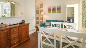A dining area with a wooden table and white chairs, a teal sofa, and a mirror above the table. - Holmefield (Bakewell)