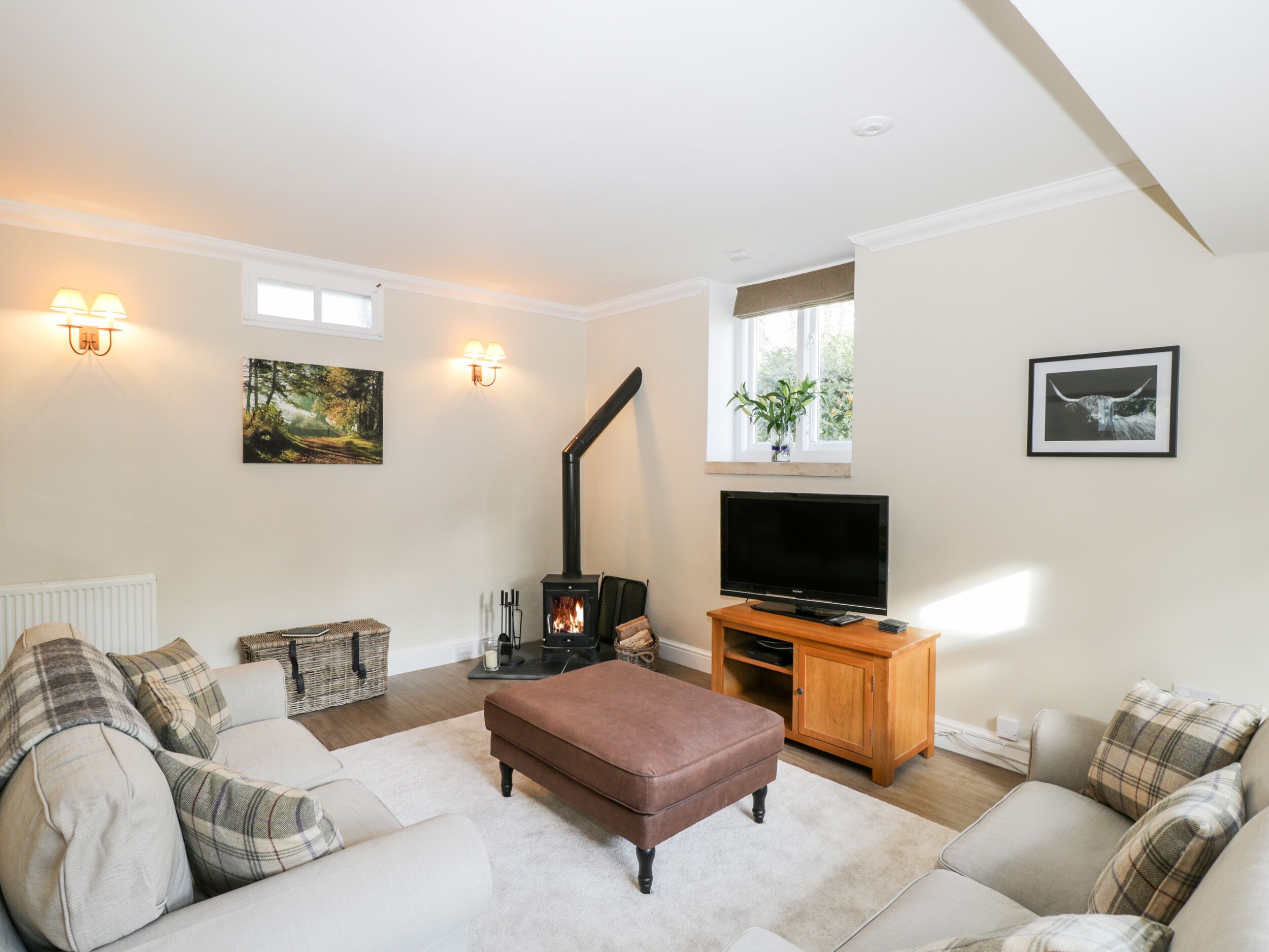 Ein Wohnzimmer mit einer Couch, einem Fernseher, einem Kamin und Wandleuchten.