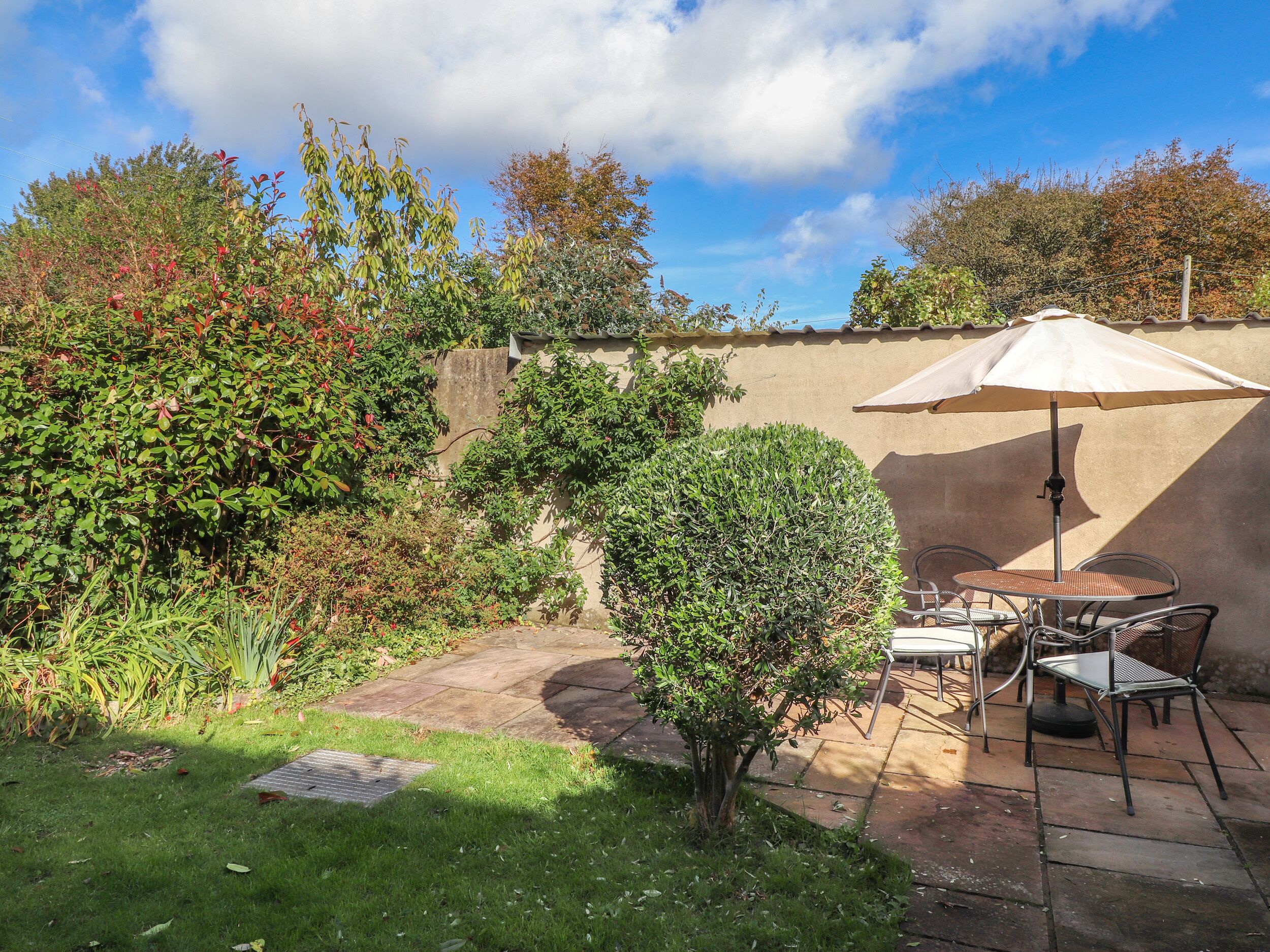 Eine Terrasse mit Tisch und Stühlen, umgeben von einem Garten und einer Mauer.