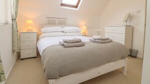 A bedroom with a bed, two bedside tables, a dresser, a window with a view, and a ceiling light. - Y Bwthyn, Newport (Newport)