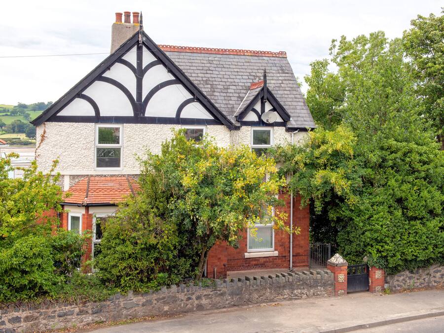 A traditional house with a steeply pitched roof, white walls, and black trim.