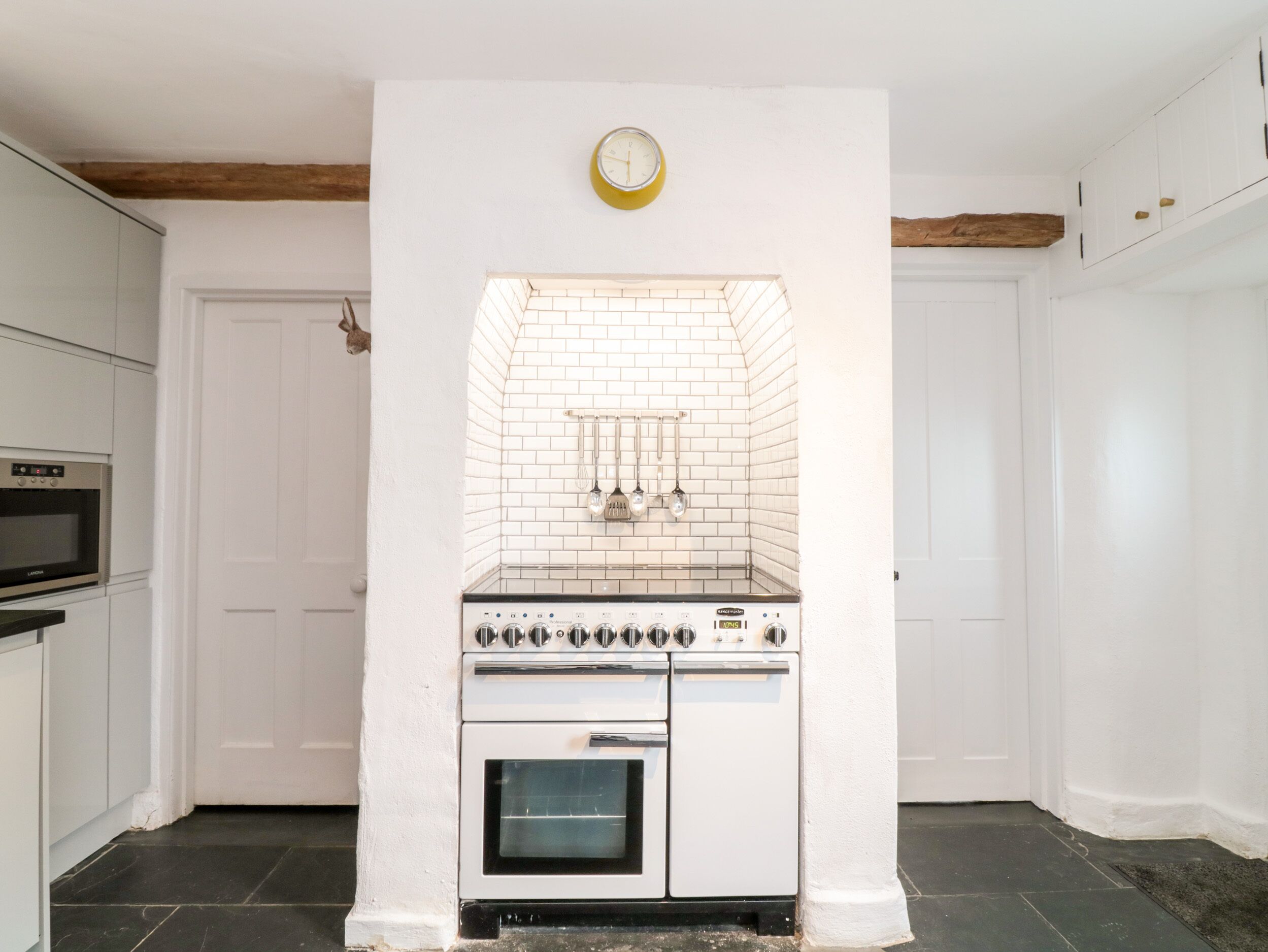 A kitchen with white cabinets, a built-in oven, and a clock on the wall.
