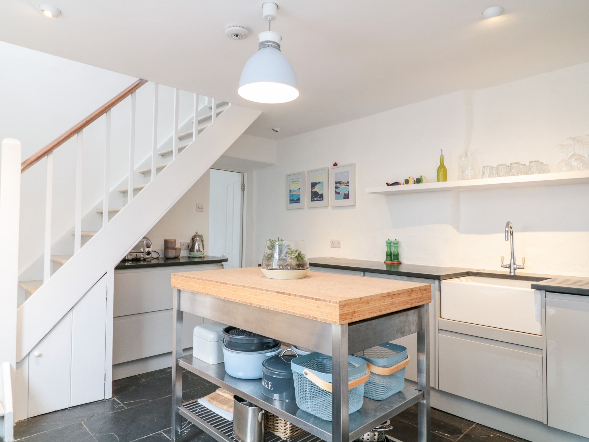 Una cocina moderna con una isla de madera, electrodomésticos de acero inoxidable y una escalera blanca.