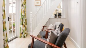 Un escalier avec des balustrades blanches, une main courante en bois et un banc rembourré agrémenté de coussins.