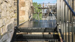 Una escalera de metal con barandilla que lleva a un muro de piedra.