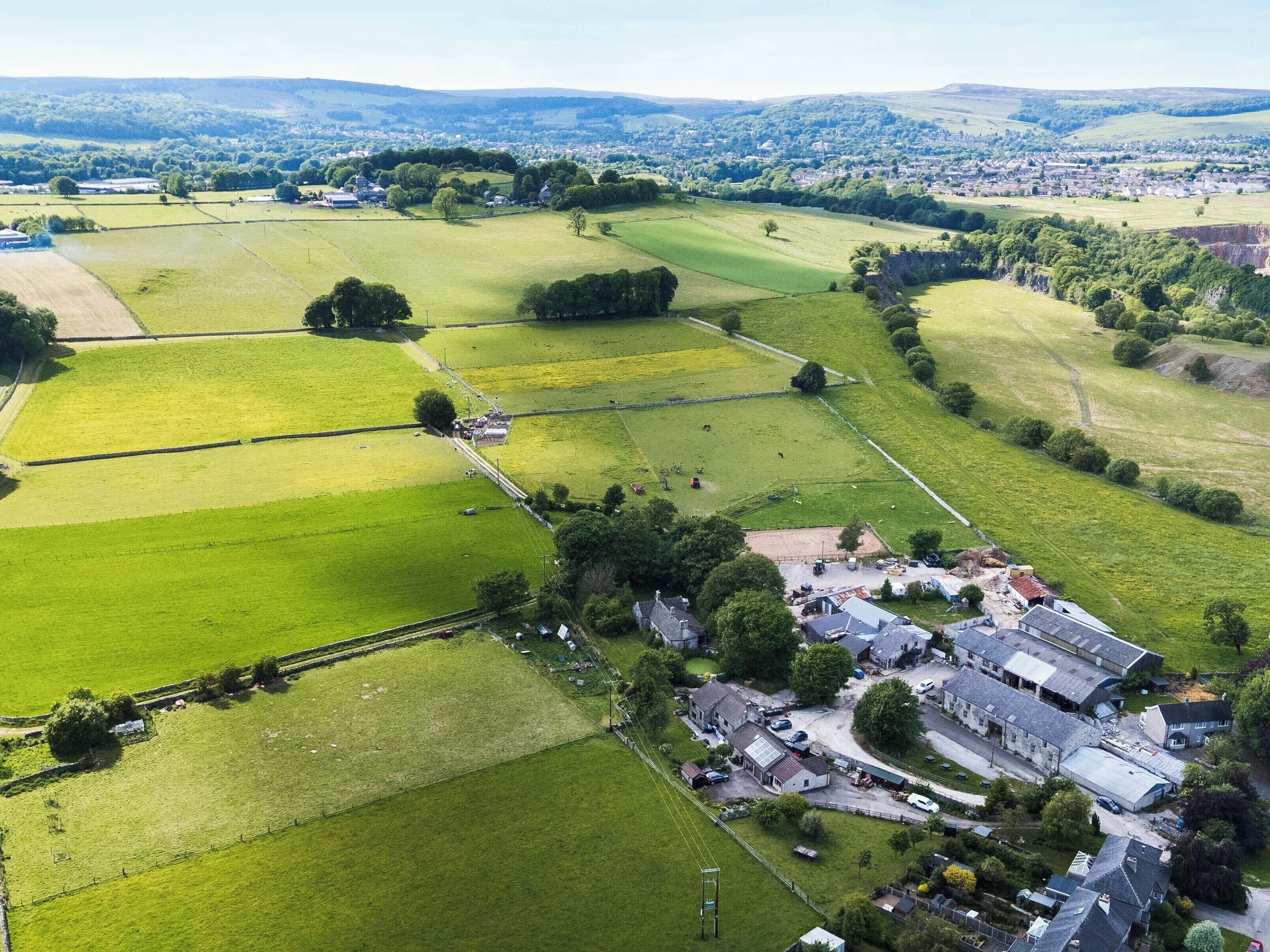 Une vue aérienne d’une zone rurale avec des champs, un petit village et un grand ensemble de bâtiments.