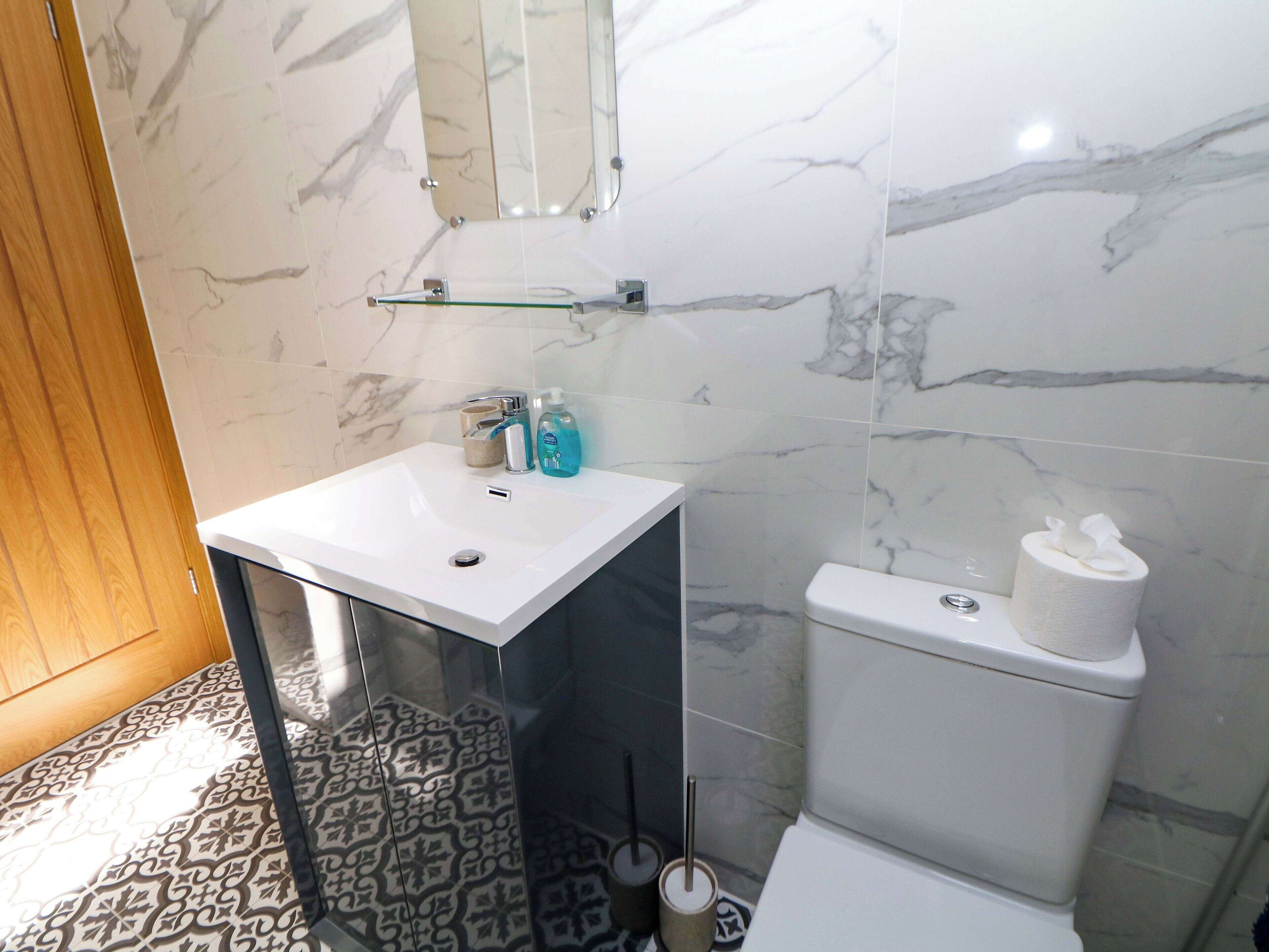 Une salle de bain avec un lavabo blanc, un miroir et des toilettes.