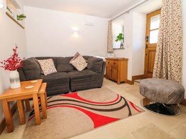 A living room with a sofa, a small wooden cabinet, a table with a vase, and a patterned rug.