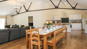 Amplia sala de estar con mesa de comedor para cuatro personas, un sofá y una cocina al fondo.