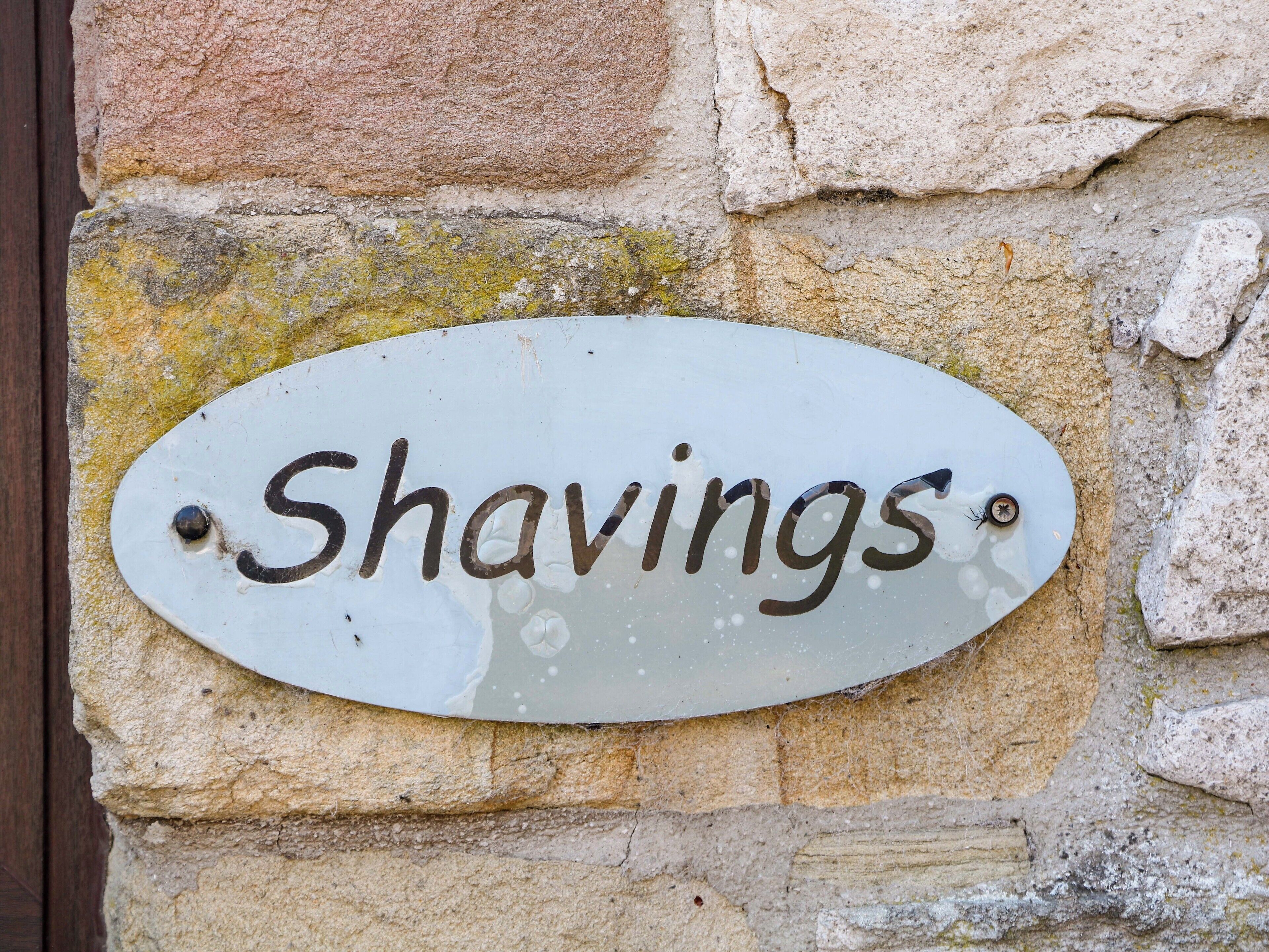 En vejrbidt skilt med ordet "Shavings" på en stenvæg.