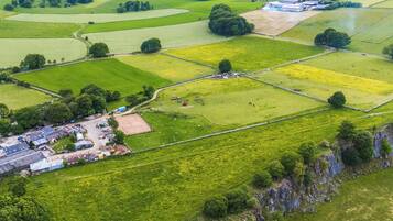 An aerial view of a rural landscape with fields, a small cluster of buildings, and a stone wall.