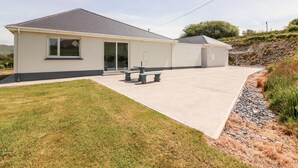 A single-story building with a flat roof, a covered patio area, and a small garden. - Coolnaharragill Lower (Glenbeigh)
