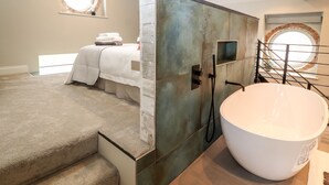 A modern bathroom with a freestanding bathtub, a shower, and a large mirror. - The Old Workshop (Denbigh)