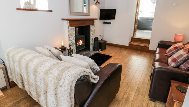 A cozy living room with a fireplace, leather sofas, a television, and a wooden floor.