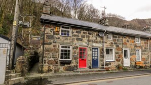 A stone building with a red door, a blue door, and a bench outside.