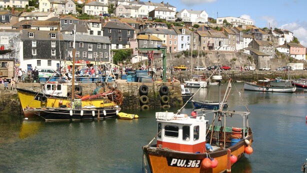 A harbor with boats docked, a town in the background, and a clear sky. - Valley View (St Austell)