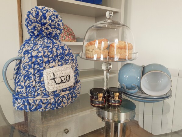 A kitchen area with a blue and white crocheted item labeled "tea," a glass display case with pastries, and two jars of "Baskin's Berry" ice cream.