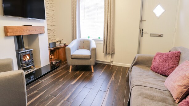 A living room with a fireplace, a sofa, a chair, and a television. - Scarborough Cottage (Driffield)