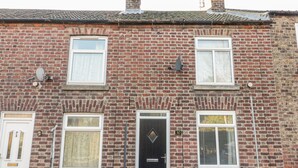 A two-story brick house with a black front door, white-framed windows, and a satellite dish on the left side. - Scarborough Cottage (Driffield)