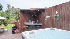 Um quintal com hidromassagem, churrasqueira e um deck de madeira.