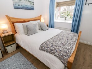 A neatly made bed with a wooden headboard, a bedside lamp, and a small nightstand.