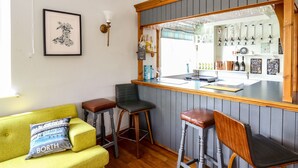 A bar area with stools, a counter, and a view of the bar. - Llety Ceiro (Bow Street)