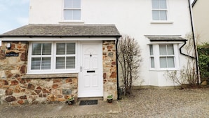 A two-story house with a white exterior, stone foundation, and a small front porch. - Ty'r Winllan (Newport)