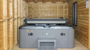 A hot tub in a wooden cabin with a small wooden bench in front. - 4 Ty Rhosyn (Porthmadog)