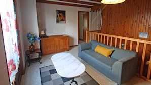 A cozy living room with a sofa, a small table, and a wooden cabinet. - Family-Friendly Countryside Cottage with Modern Amenities, Near Thermal Baths and Nature Spots (Le Val-d'Ajol)