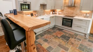 A modern kitchen with grey cabinets, a wooden countertop, and a tiled floor. - Nana's Cottage (Camborne)