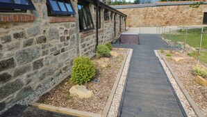 A stone building with a wooden deck and a small garden area. - Nana's Cottage (Camborne)