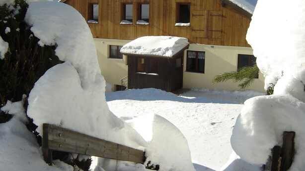 A wooden chalet with a snow-covered roof, a wooden door, and windows. - Cozy Mountain Retreat with Garage, BBQ & Wifi in La Bresse (La Bresse)