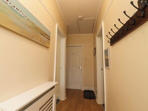 Un pasillo con una puerta blanca, un perchero y un cuadro en la pared.