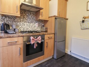 A kitchen with wooden cabinets, a stainless steel refrigerator, a gas stove, and a microwave.