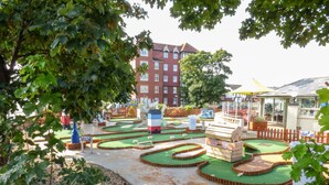 Ein Minigolfplatz mit einem roten Gebäude im Hintergrund.