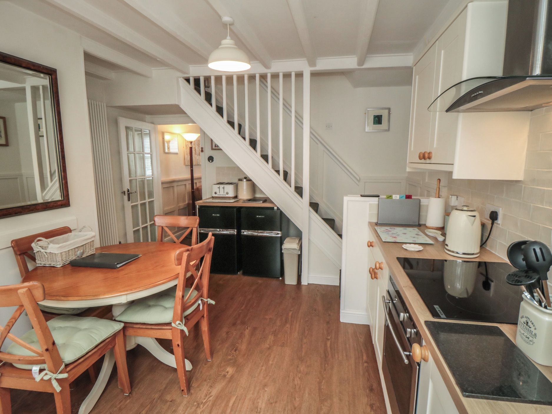 A compact kitchen with a dining area, a staircase, and a view of the adjacent living space.