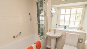 A bathroom with a bathtub, a shower, a sink, and a toilet. - Dove Cottage (Pickering)