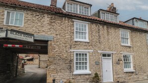 A stone building with a sign for 'BLACK SWAN Coaching Inn' and a 'DOVE COTTAGE' sign. - Dove Cottage (Pickering)