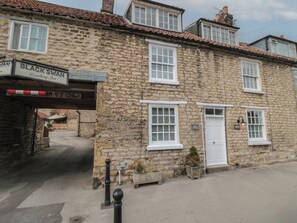 Un edificio in pietra con una insegna che riporta 'BLACK SWAN Coaching Inn' e una insegna 'DOVE COTTAGE'.