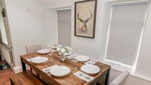 A dining room with a wooden table set for six, white plates, and a vase with flowers. - Ivy Bank (Thornhill)